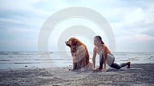 Asian woman performs yoga stretching exercises with dog at the beach. Golden Retriever lifestyle on summer holiday