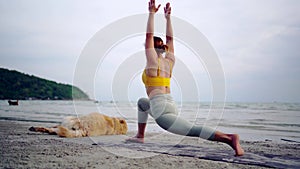 Asian woman performs yoga stretching exercises with dog at the beach. Golden Retriever lifestyle on summer holiday