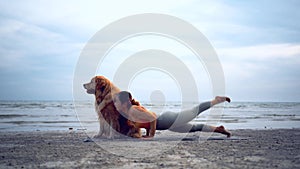 Asian woman performs yoga stretching exercises with dog at the beach. Golden Retriever lifestyle on summer holiday