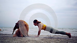 Asian woman performs yoga stretching exercises with dog at the beach. Golden Retriever lifestyle on summer holiday