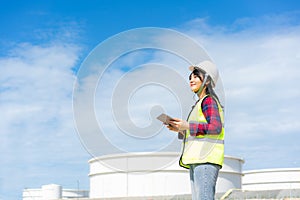 Asian woman petrochemical engineer working with digital tablet Inside oil and gas refinery plant industry factory at night for