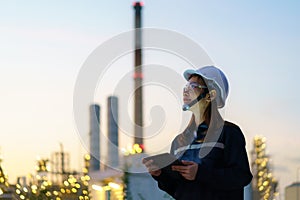 Asian woman petrochemical engineer working at night with digital tablet Inside oil and gas refinery plant industry factory at