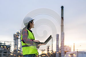 Asian woman petrochemical engineer working at night with notebook Inside oil and gas refinery plant industry factory at night for