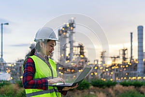 Asian woman petrochemical engineer working at night with notebook Inside oil and gas refinery plant industry factory at night for