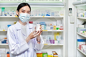 Asian woman pharmacist holding a medicine bottle in pharmacy