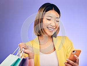 Asian woman, phone and shopping bag in studio, texting and smile for deal, sale or discount by background. Japanese girl