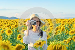 An Asian woman, a photographer, using a film camera to take photos on social media at full bloom sunflower field in travel