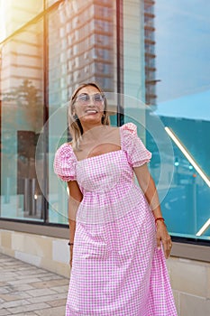 Asian woman in a pink dress and sunglasses with an umbrella is sitting in the center of the city