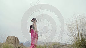 Asian woman with pink long skirt walking outdoors in a desolate area