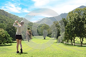 Asian woman playing golf on a beautiful natural golf course