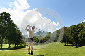 Asian woman playing golf on a beautiful natural golf course