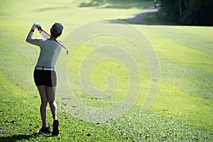 Asian woman playing golf on a beautiful natural golf course