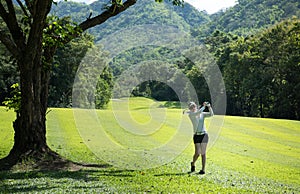 Asian woman playing golf on a beautiful natural golf course