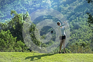 Asian woman playing golf on a beautiful natural golf course