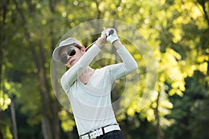 Asian woman playing golf on a beautiful natural golf course