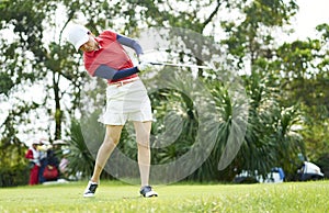 Asian woman playing golf swinging golf club for teeing off in course