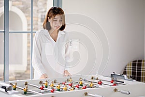 An Asian woman playing soccer football table board game. Leisure activity and sports entertainment concepts