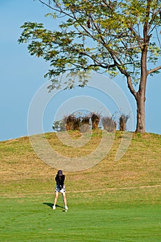 An asian woman plays golf