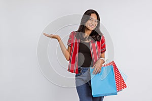 asian woman pointing on her side while bring the shoppings bags photo