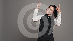 Asian woman pointing at something upwards in studio