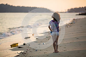 Asian woman on a polluted tropical beach.