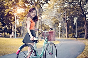 Asian woman portrait in public park with bicycle. People and Lifestyles concept. Relaxation and activity theme.
