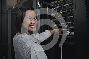 Asian woman, portrait smile and technician by server for cabling, networking or system maintenance at office. Happy