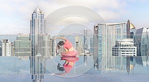 Asian woman pose yoga action on hotel rooftop with Bangkok city and swimming pool background