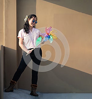 Asian woman posts and play Windmill Toy colourful rainbow colour on the building rooftop in sunset time