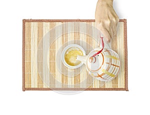 Asian woman pour hot tea from a teapot into a cup of tea on wood mat isolated on white background