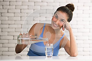 Asian woman pouring water from bottle into glass in the room