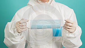 Asian woman in PPE suit ,medical gloves and hloding face mask  or medical mask on green, Tiffany Blue background