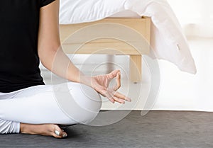 Asian woman practicing yoga, doing Half Lotus pose with mudra gesture on mat in the bedroom