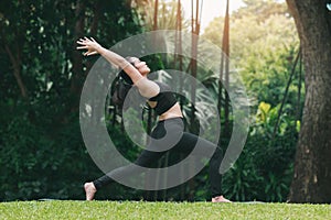 Asian woman practicing yoga in High Lunge, Crescent pose on the mat in outdoor park