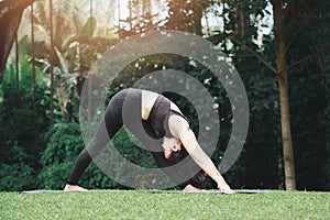 Asian woman practicing yoga in Intense Side Stretch Pose on the mat in outdoor park