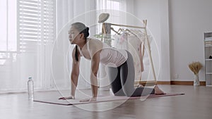 Asian woman practicing yoga pose Cat and Cow at home