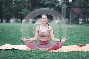 Asian woman practicing yoga in Root Bond, Mula Bandha pose on the mat in outdoor park