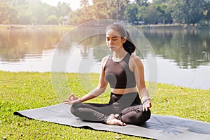 Asian woman practicing yoga in Root Bond, Mula Bandha pose on the mat in outdoor park photo