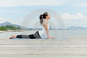 Asian woman practicing yoga at seashore