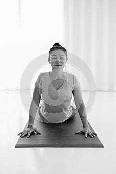 Asian woman practicing yoga , stretching in Cobra exercise, Bhujangasana pose, working out indoor,monochrome