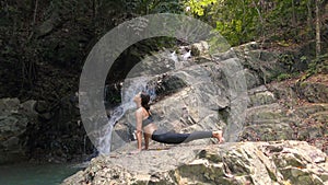 Asian Woman Practicing Yoga at the Waterfall