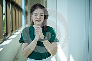 Asian woman praying morning near the window at church, Hands folded in prayer concept for faith, spirituality and religion, Church