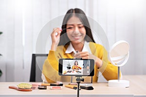 Asian woman present beauty cosmetic product and broadcast live video to social network by internet at home, beauty blogger concept