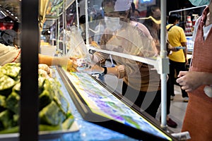 Asian woman in a protective mask,buying food in food court at shopping mall after Coronavirus quarantine or Covid-19 with plastic