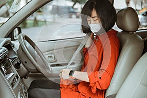 Woman in protective mask driving a car on road. Safe traveling fasten seat belt