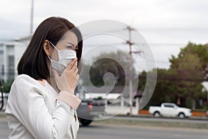 Asian woman in protective mask feeling bad on the street in the city with air pollution., Black short hair suffer from sick and we