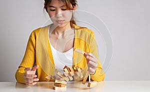 Asian woman pulling wood block and tower collapses, Management of risks and economic instability concept