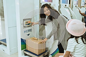 Asian woman put the cardboard on the luggage scale