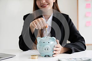 Asian woman putting coin into piggy bank. Saving money with coins Step into a business that is growing to be successful and save