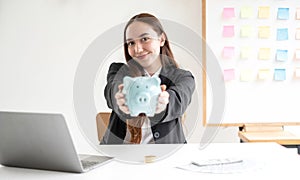 Asian woman putting coin into piggy bank. Saving money with coins Step into a business that is growing to be successful and save